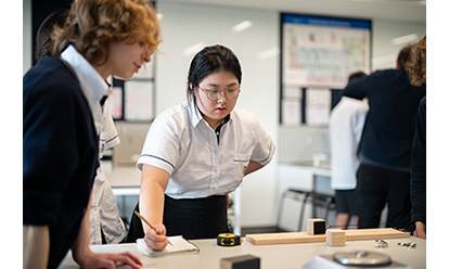 Student wearing protective goggles and a lab coat conducting an experiment